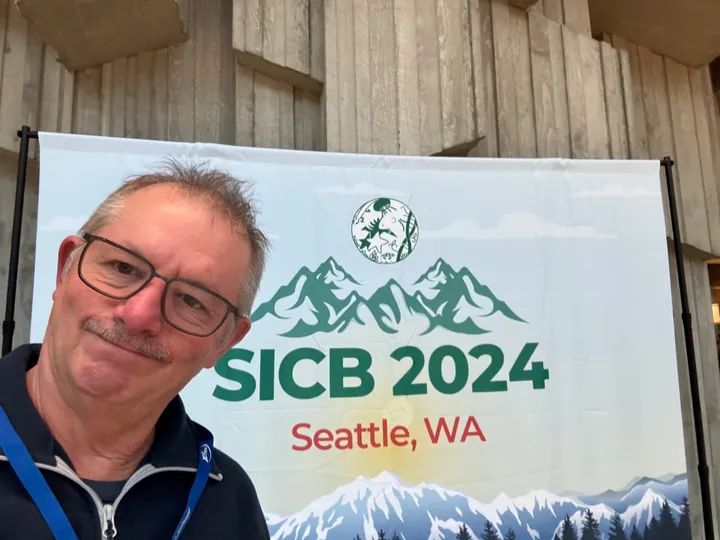 Don Powers in front of the SICB 2024 Seattle, WA welcome banner
