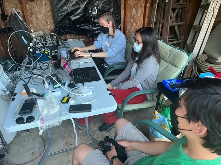 Three Team Torpor members working at laptops and equipment in the shed turned torpor lab